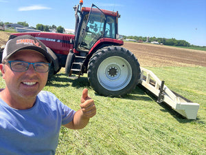 Man giving a thumbs up in front of a red tractor on a farm